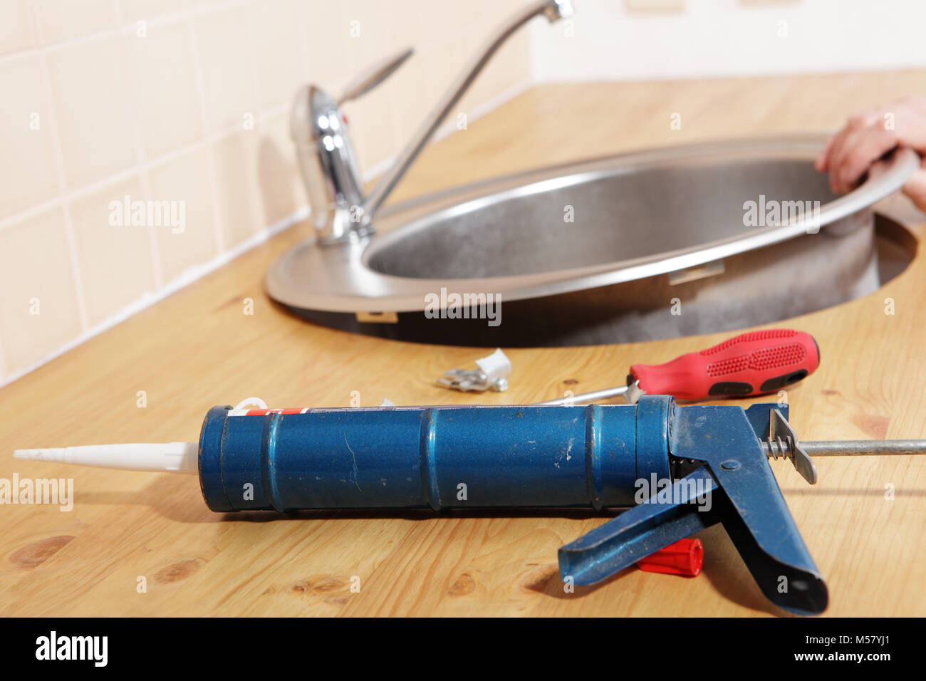 Pistola erogatrice con sigillante al silicone contro il lavello da cucina il processo di installazione Foto Stock