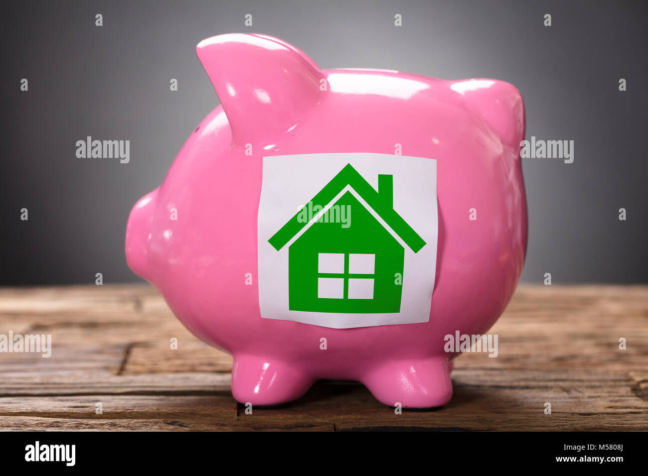 Vista dettagliata del libro verde sulla casa rosa piggybank su legno Foto Stock