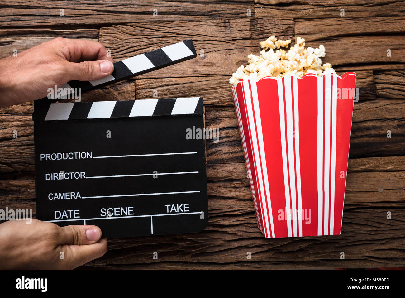 Primo piano delle mani clapperboard da pop-corn su legno Foto Stock