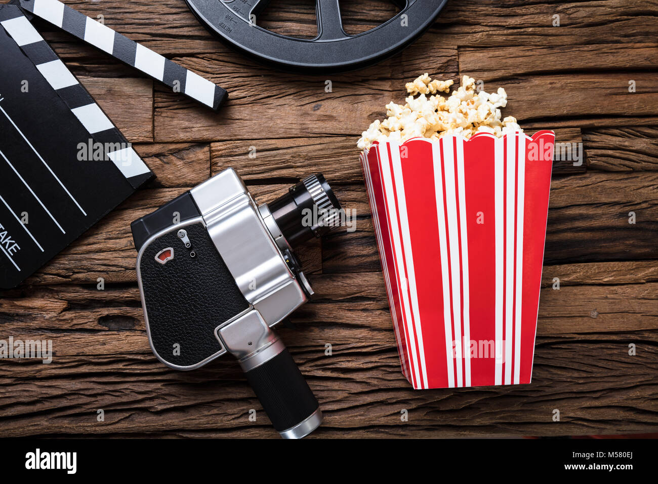 Primo piano della macchina fotografica del film con battaglio board e popcorn su legno Foto Stock