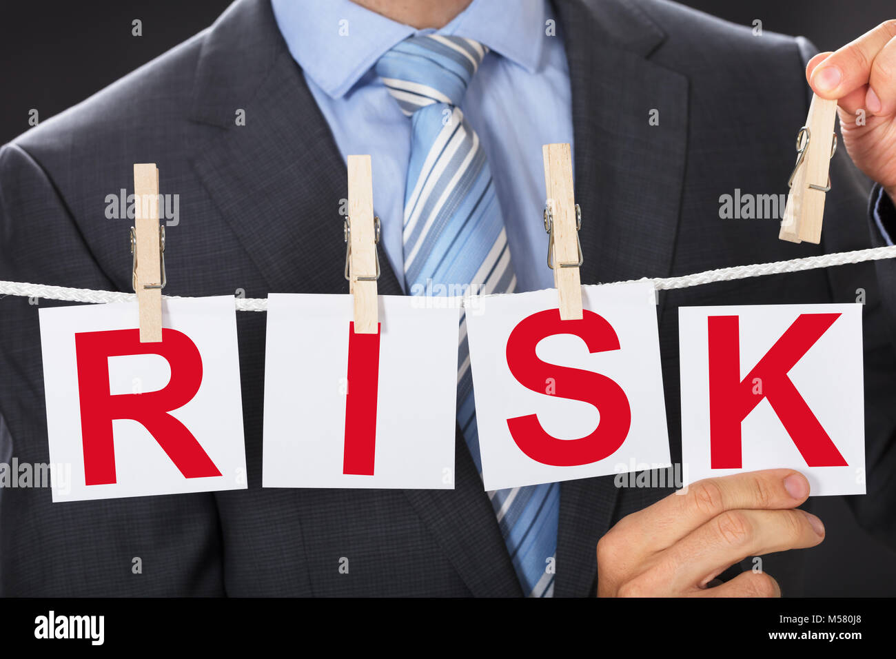 Vista dettagliata sezione mediana di imprenditore pinning schede di rischio su stendibiancheria Foto Stock