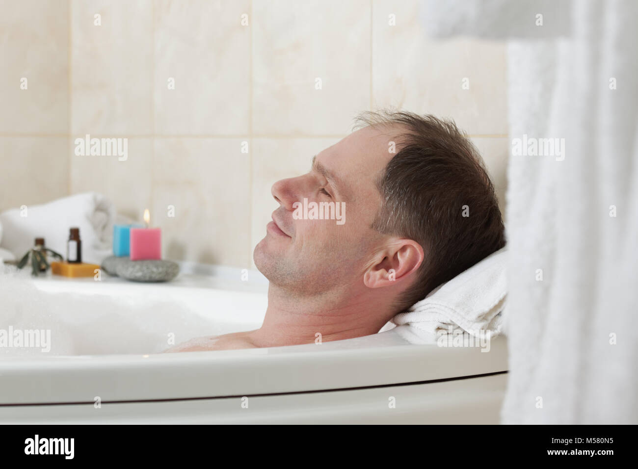 Uomo adulto avente una vasca da bagno con olio essenziale Foto Stock