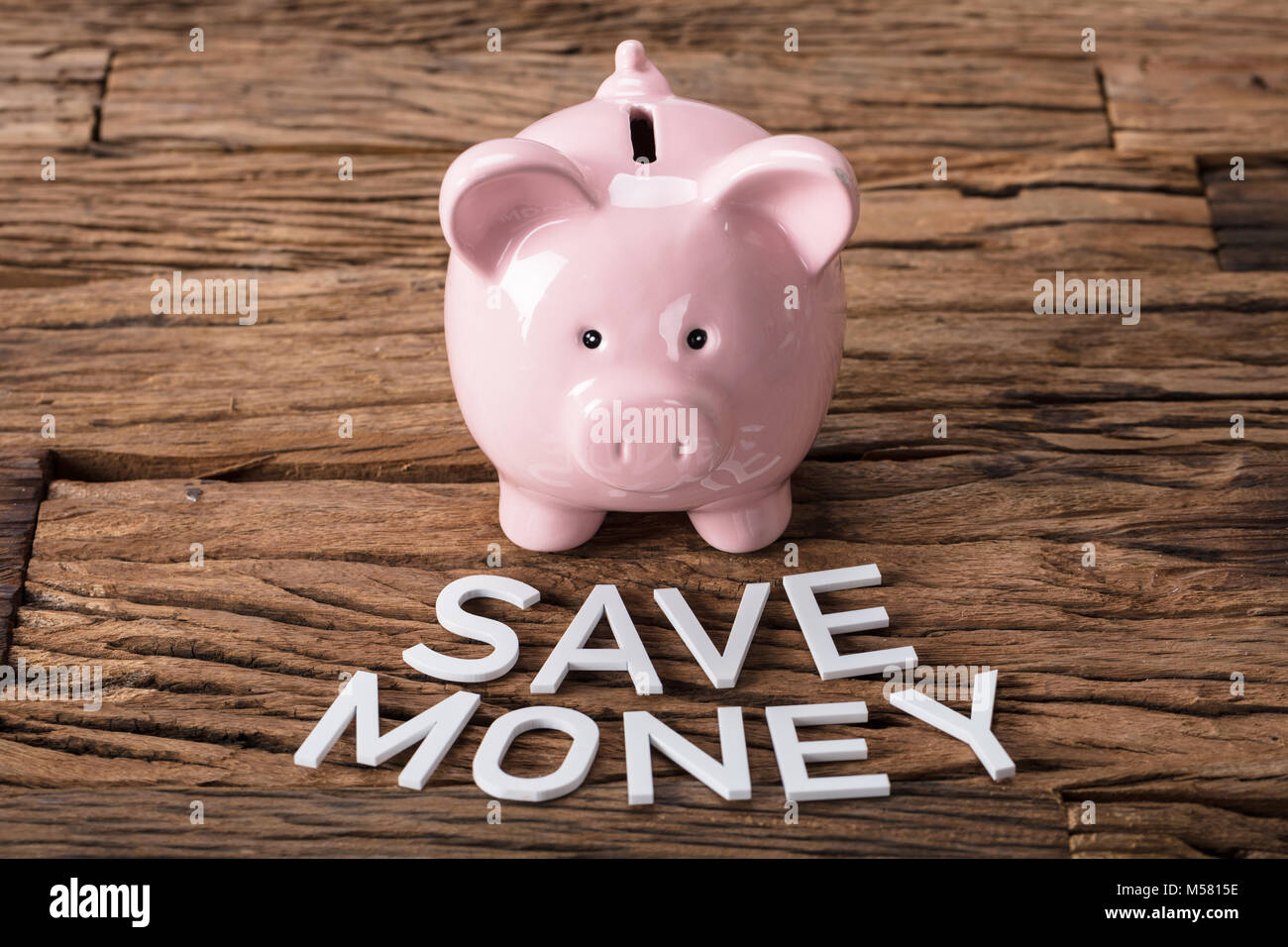Primo piano della piggybank da risparmiare denaro testo sul tavolo di legno Foto Stock