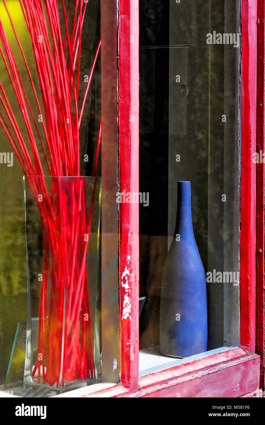 Vecchia bottiglia di vino in rosso sul telaio di una finestra e canne Foto Stock