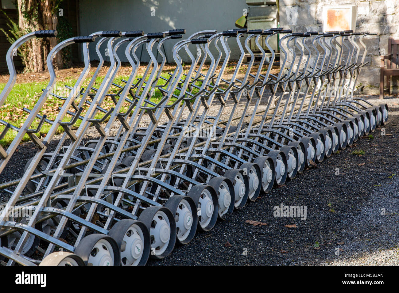 Close up di un allineati carrelli da golf per il noleggio attaccato a sistemi di erogazione Foto Stock