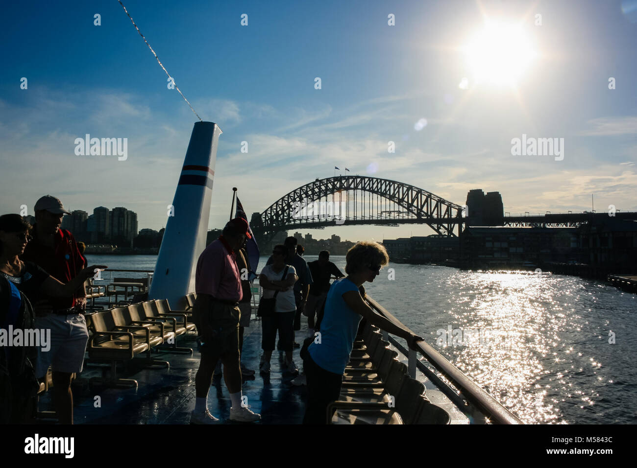 Persone che guardano il Ponte del Porto di Sydney da un trasferimento in barca al tramonto Foto Stock