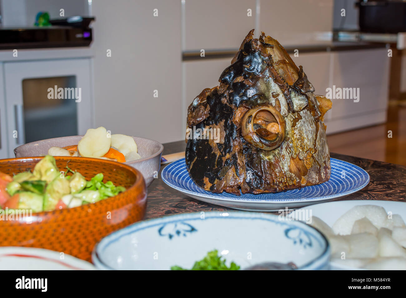 Una grande testa di pesce su una piastra con il bulbo oculare visibile nella presa, servita come parte di una cena Giapponese. Foto Stock