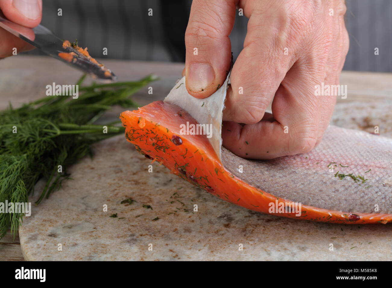 Cuocere la rimozione di pelle da salate filetto di salmone su un tagliere Foto Stock