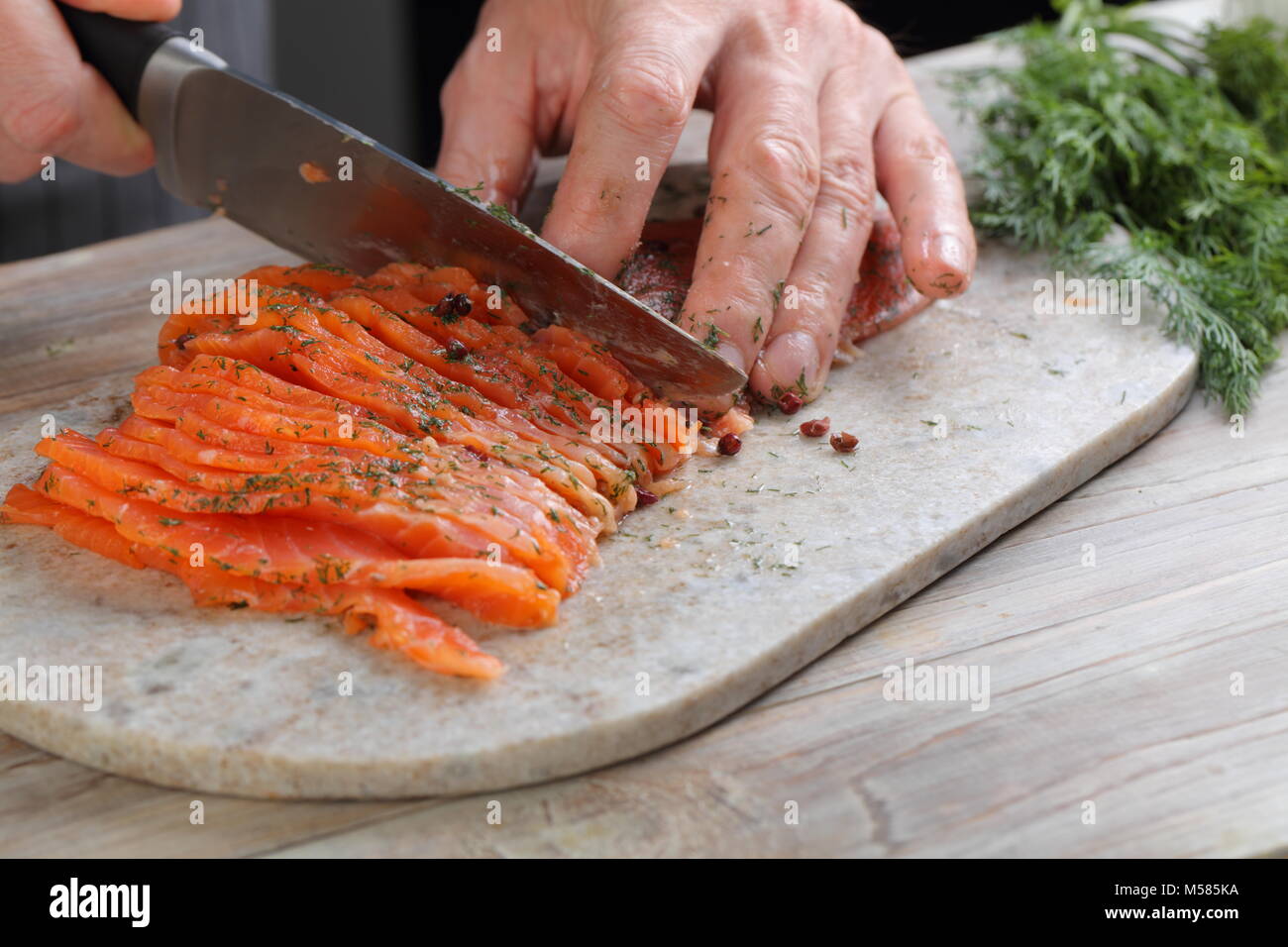 Cuocere per affettare il salmone salato su un tagliere Foto Stock