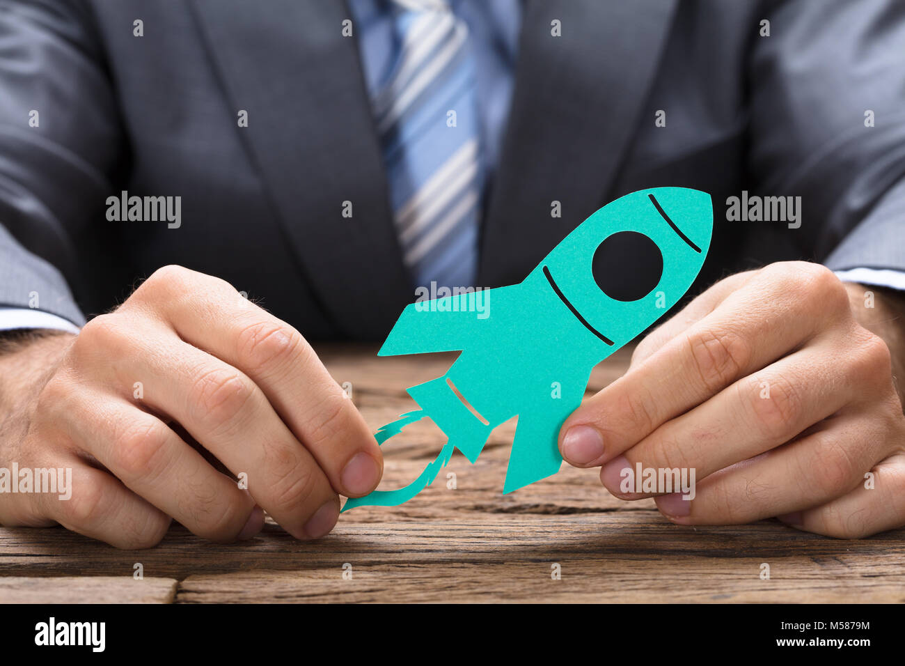 Sezione mediana di imprenditore azienda libro verde razzo al tavolo di legno Foto Stock