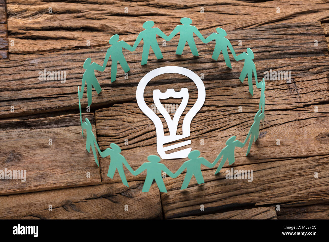 Elevato angolo di visione del libro verde il team Aziende che circonda la lampadina luce sul tavolo di legno Foto Stock