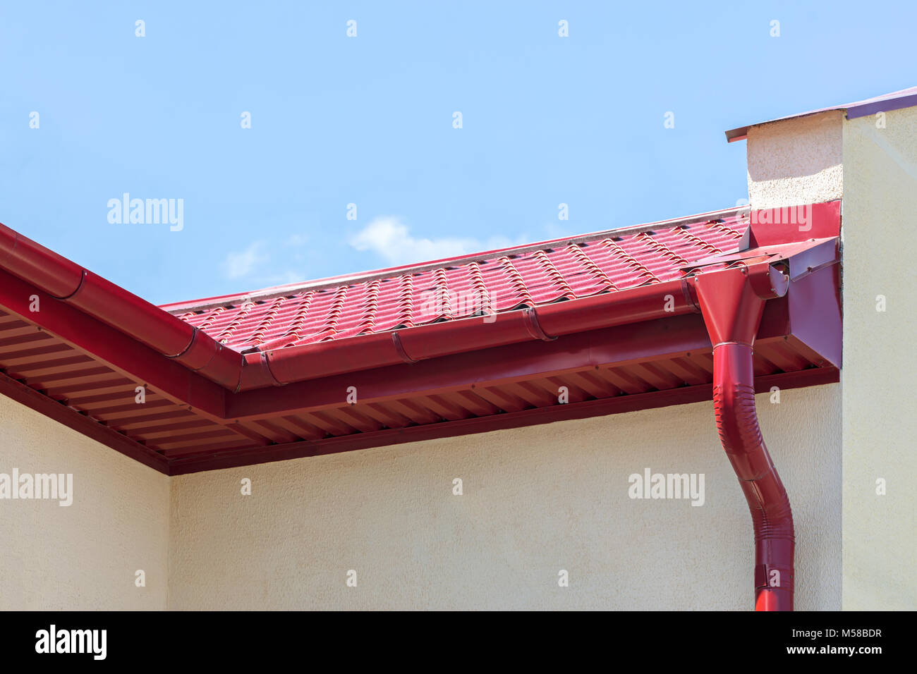 Pioggia moderno canaletta con metallo rosso la grondaia sul tetto della casa con cielo blu in background Foto Stock