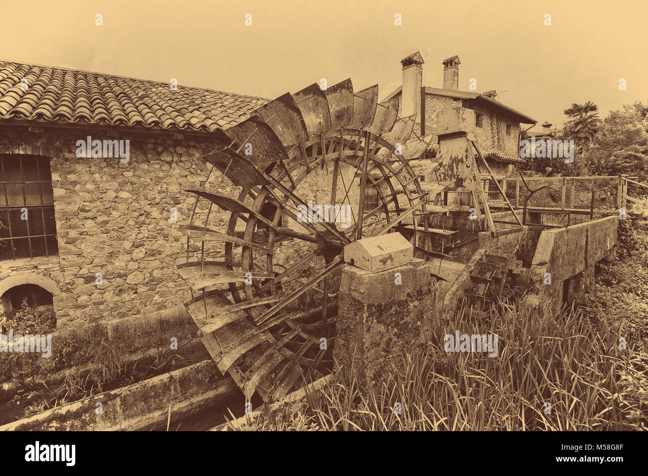 Vecchie ruote di acqua di un mulino ad acqua. In stile vintage foto. Aggiunta di grano per dare una vecchia foto effetto. Foto Stock
