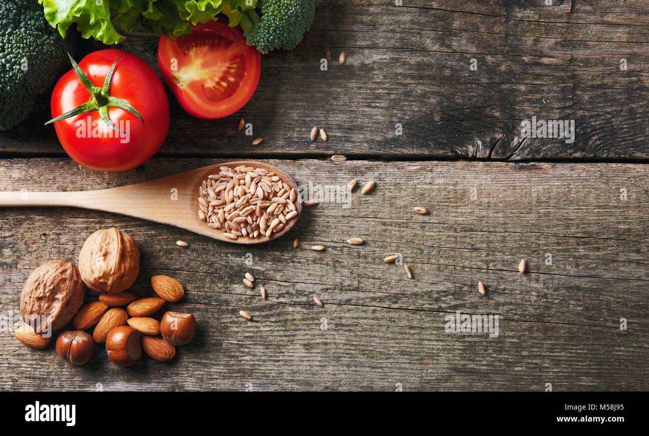 Il cibo sano con semi, pomodori e insalata su un tavolo di legno Foto Stock