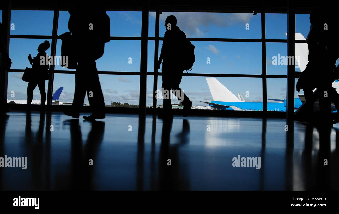 I viaggiatori con le valigie e bagagli in aeroporto per raggiungere a piedi le partenze davanti alla finestra, silhouette Foto Stock