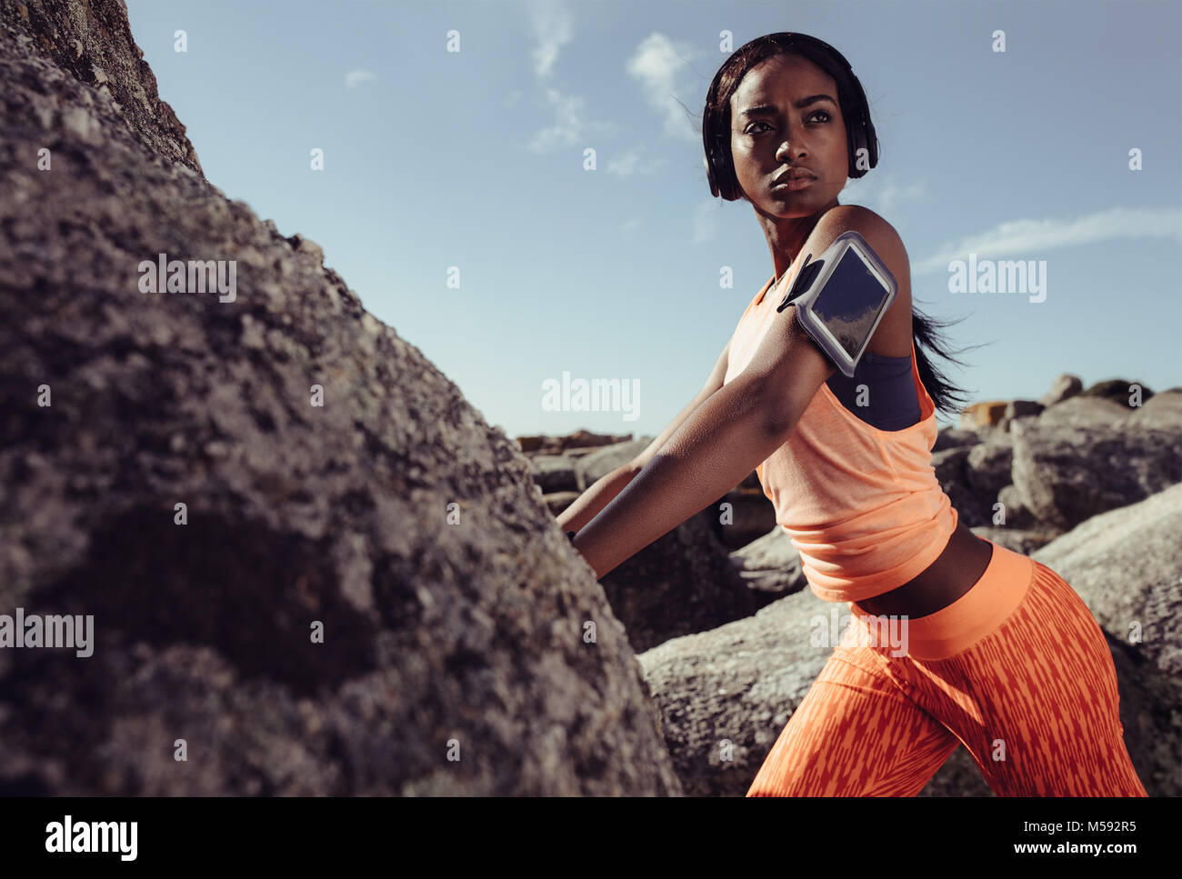 Fit donna africana in piedi sulla roccia in spiaggia durante la sessione di allenamento. donna fitness in abbigliamento sportivo durante una sessione di allenamento all'aperto. Foto Stock