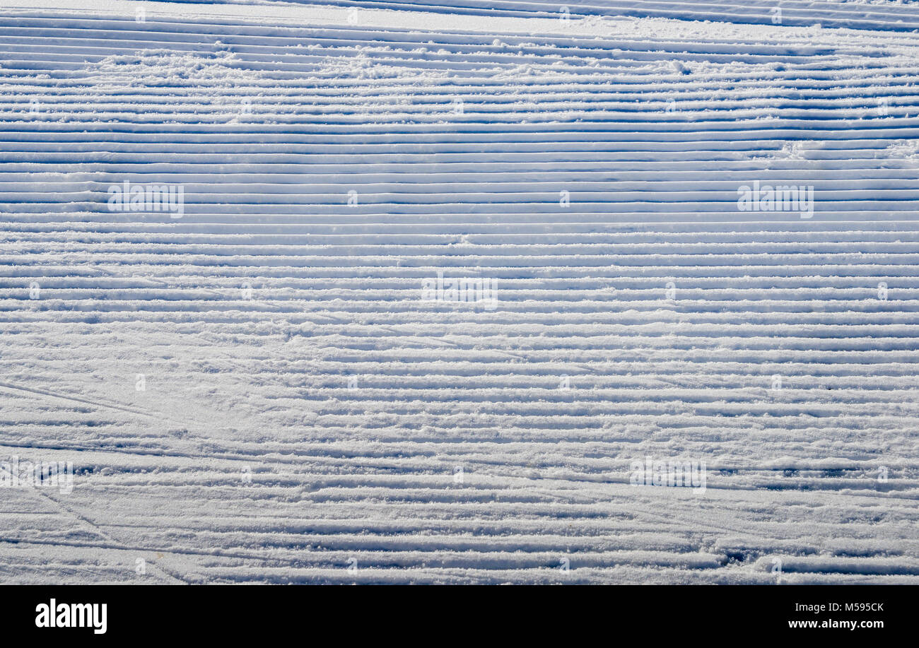 Recentemente curato la neve sulla pista da sci su una soleggiata giornata invernale Foto Stock