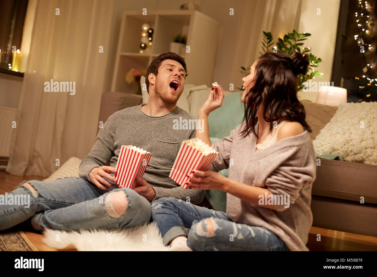 Coppia felice mangiare popcorn a casa Foto Stock