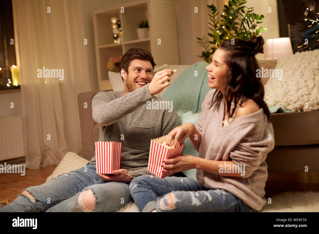 Coppia felice mangiare popcorn a casa Foto Stock