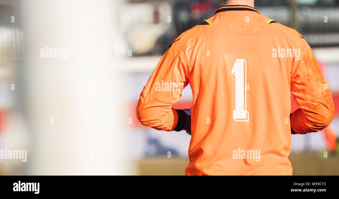 Il calcio portiere di calcio con colore arancio uniforme e numero uno, da dietro vista. Sfondo astratto, close up, dettagli, banner, spazio. Foto Stock