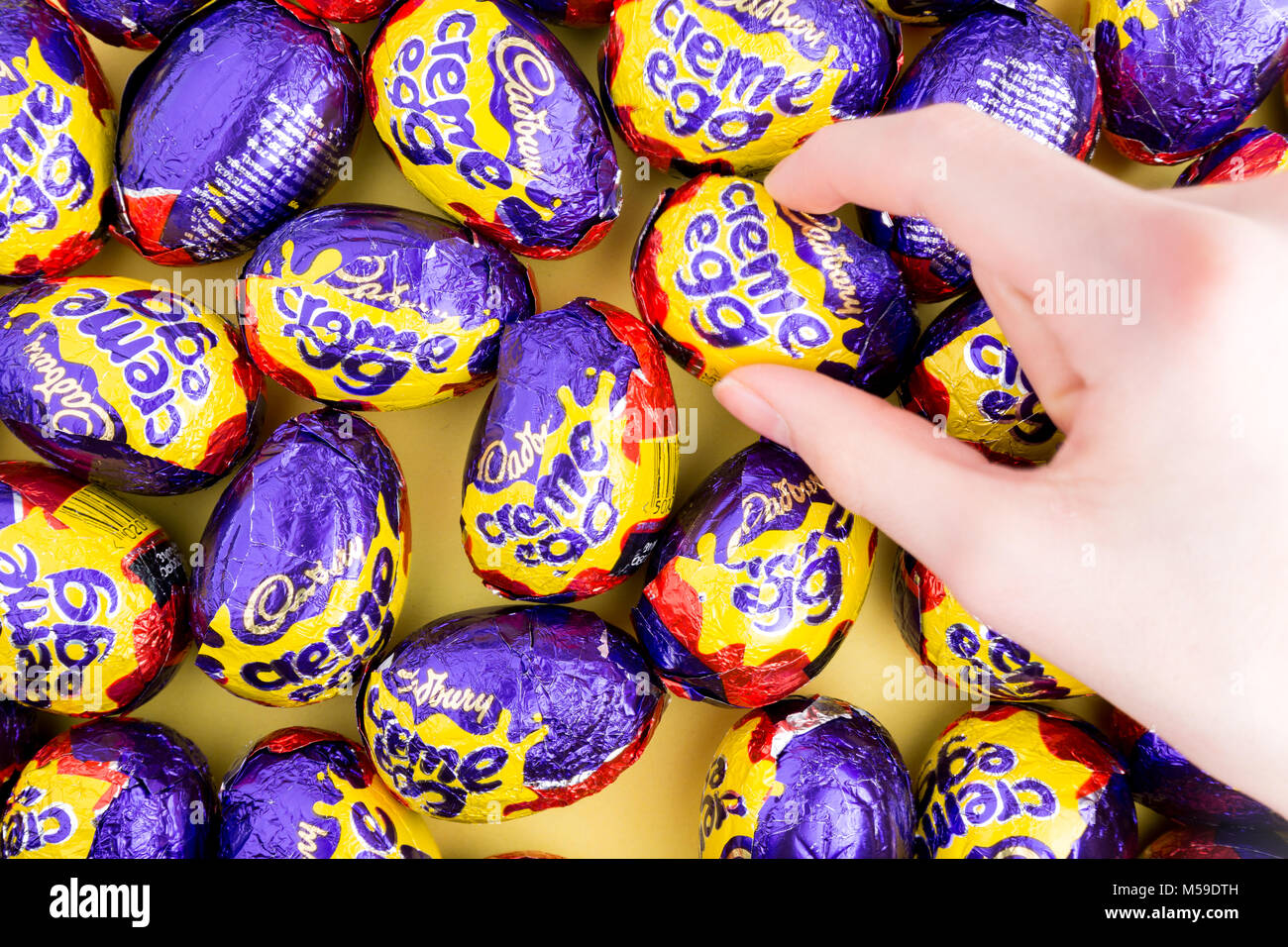 Una mano per raggiungere un Cadbury creme egg Foto Stock