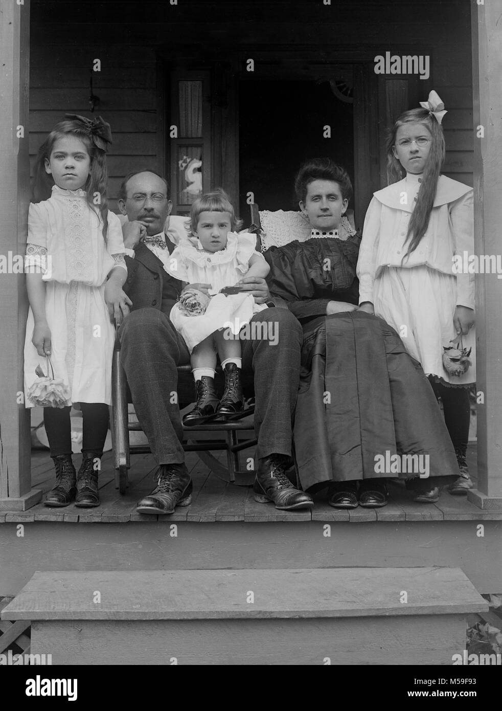 Mamma e papà cram insieme sul portico anteriore per un ritratto di famiglia, ca. 1900. Foto Stock