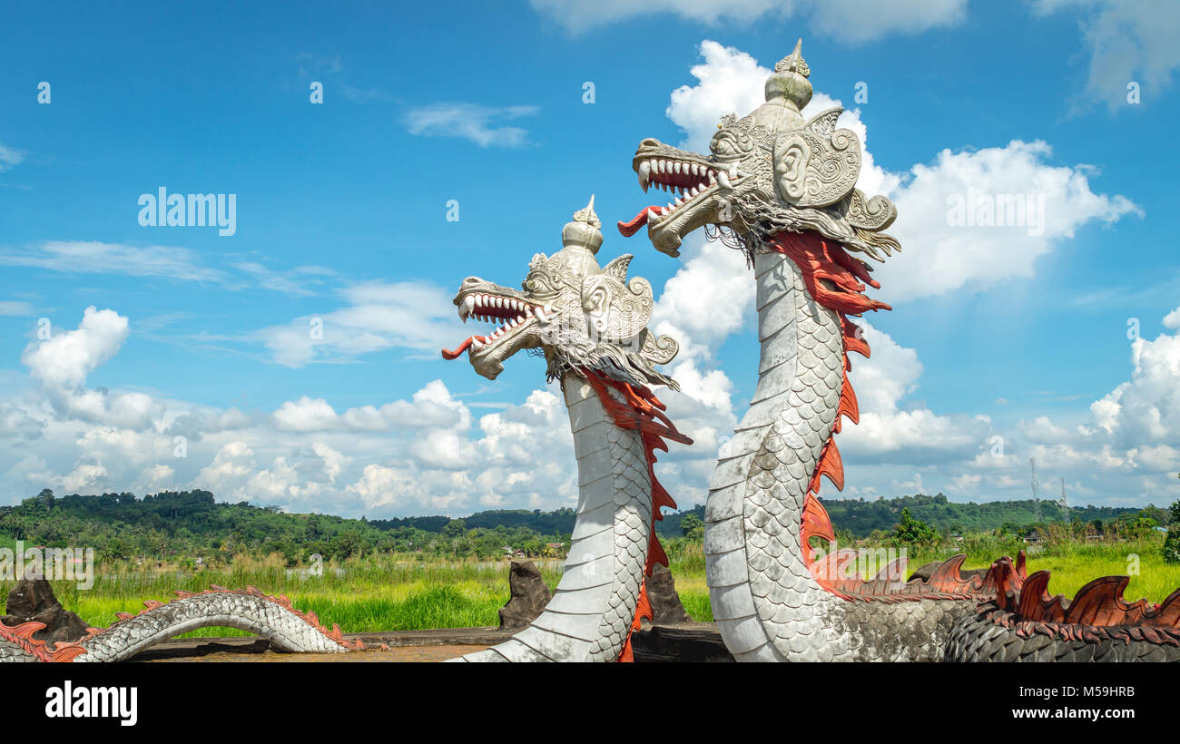 Statua di twin dragon, creature mitologiche da Kutai tribù, con belle la formazione di nubi e verde paesaggio come sfondo in Pulau Kumala, Foto Stock