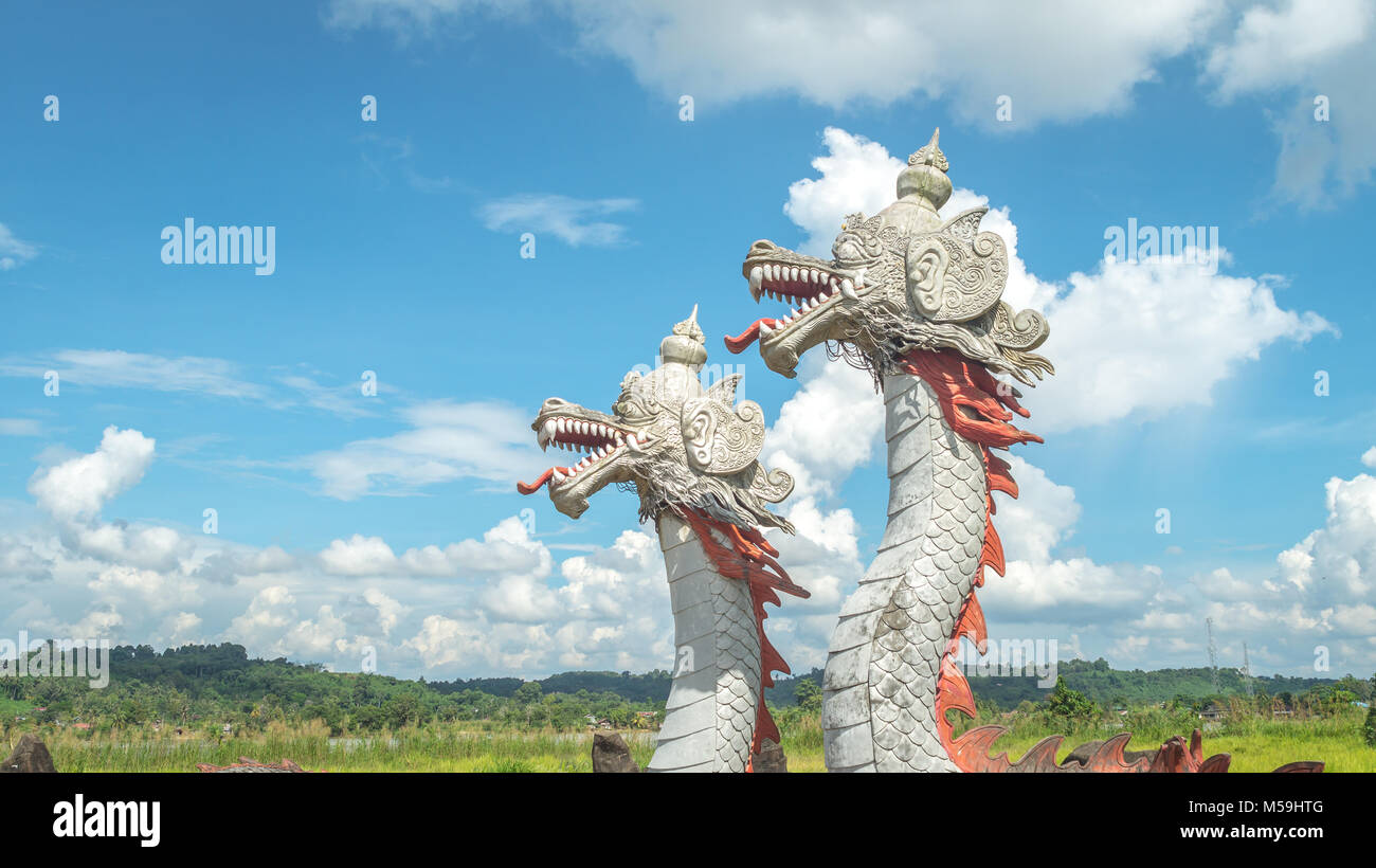 Statua di twin dragon, creature mitologiche da Kutai tribù, con belle la formazione di nubi e verde paesaggio come sfondo in Pulau Kumala, Foto Stock