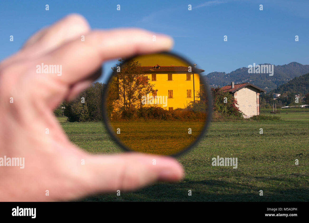 Mano azienda photohgraphic filtro arancione nel campo Foto Stock