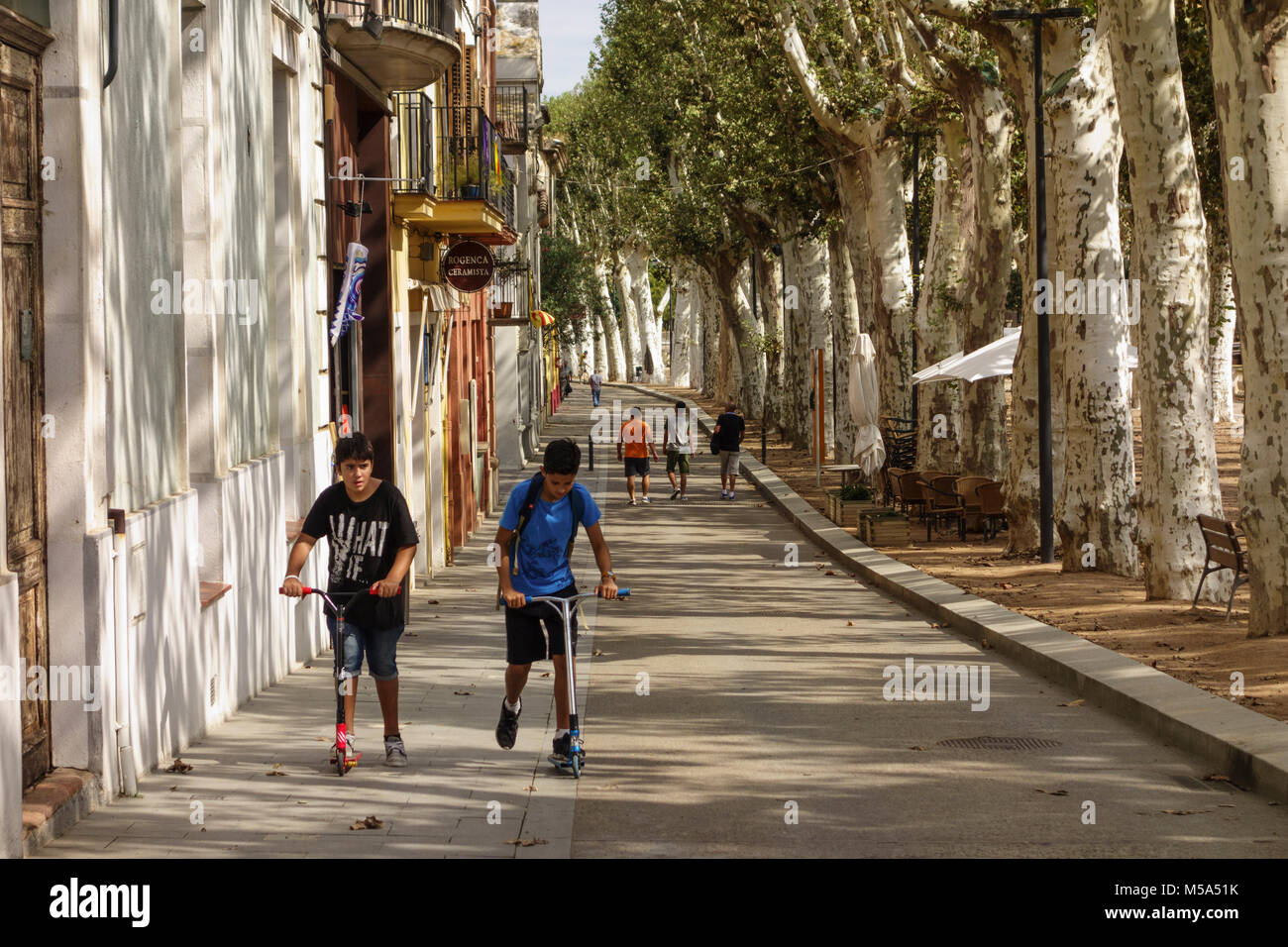La gente camminare lungo il viale alberato 'Passeig Marimon Asprer' sulla riva del fiume di Riu Daro in La Bisbal d'Emporda, Baix Empordà, Catalonia, Spai Foto Stock