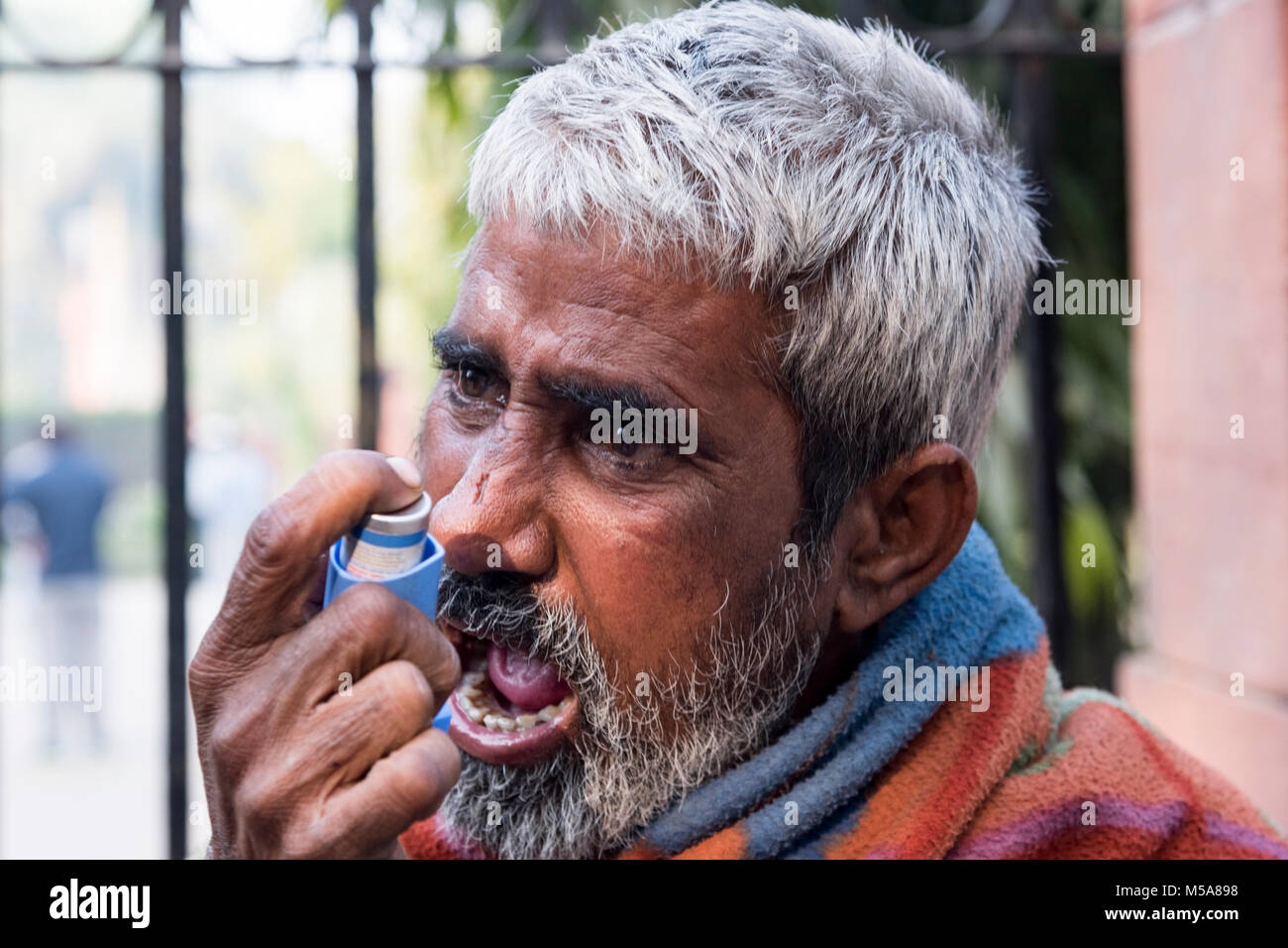 Ritratto di un povero indiano uomo prendendo inalatore per ottenere sollievo da asma Foto Stock