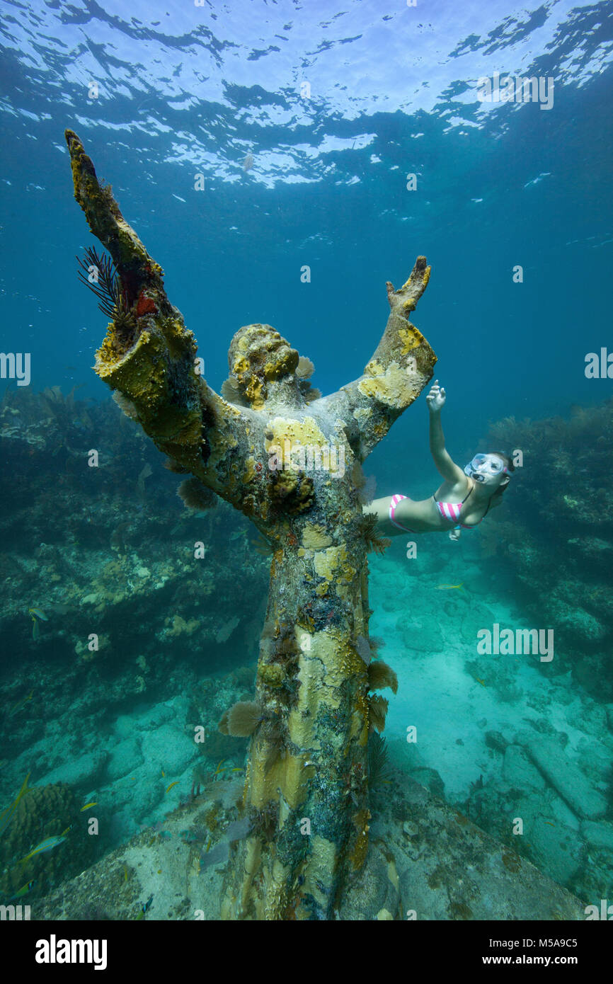 Una giovane donna boccagli vicino al Cristo degli Abissi statua, Key Largo, Florida Keys. La statua in bronzo è stata immersa nelle acque di Key Largo, Flor Foto Stock