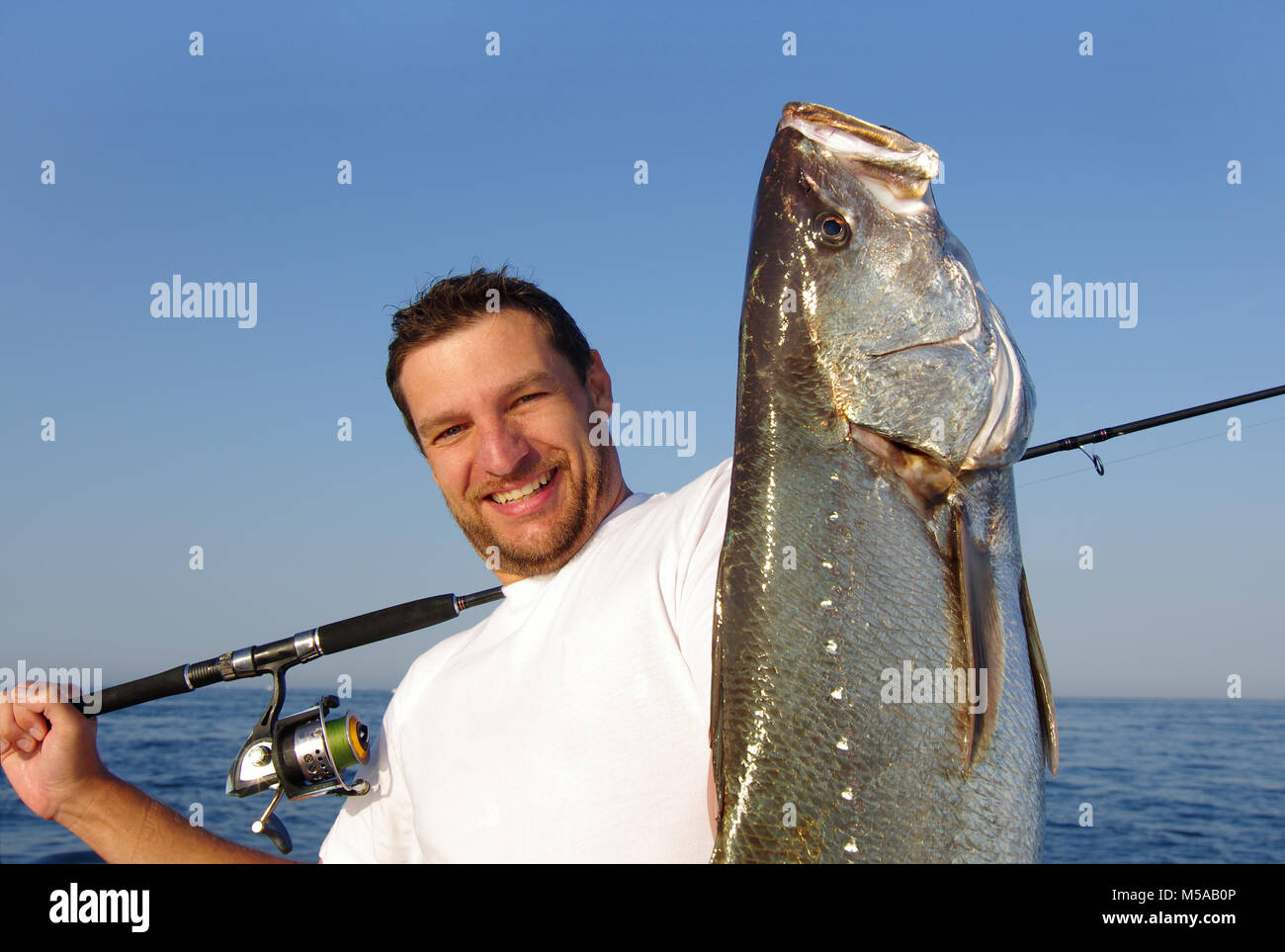 Felice pescatore tenendo un grande pesce di acqua salata Foto Stock