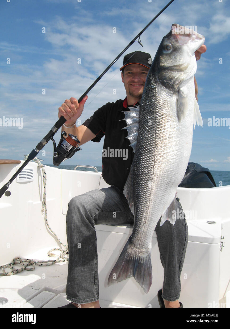 Lucky fisherman tenendo un grande mare bass Foto Stock