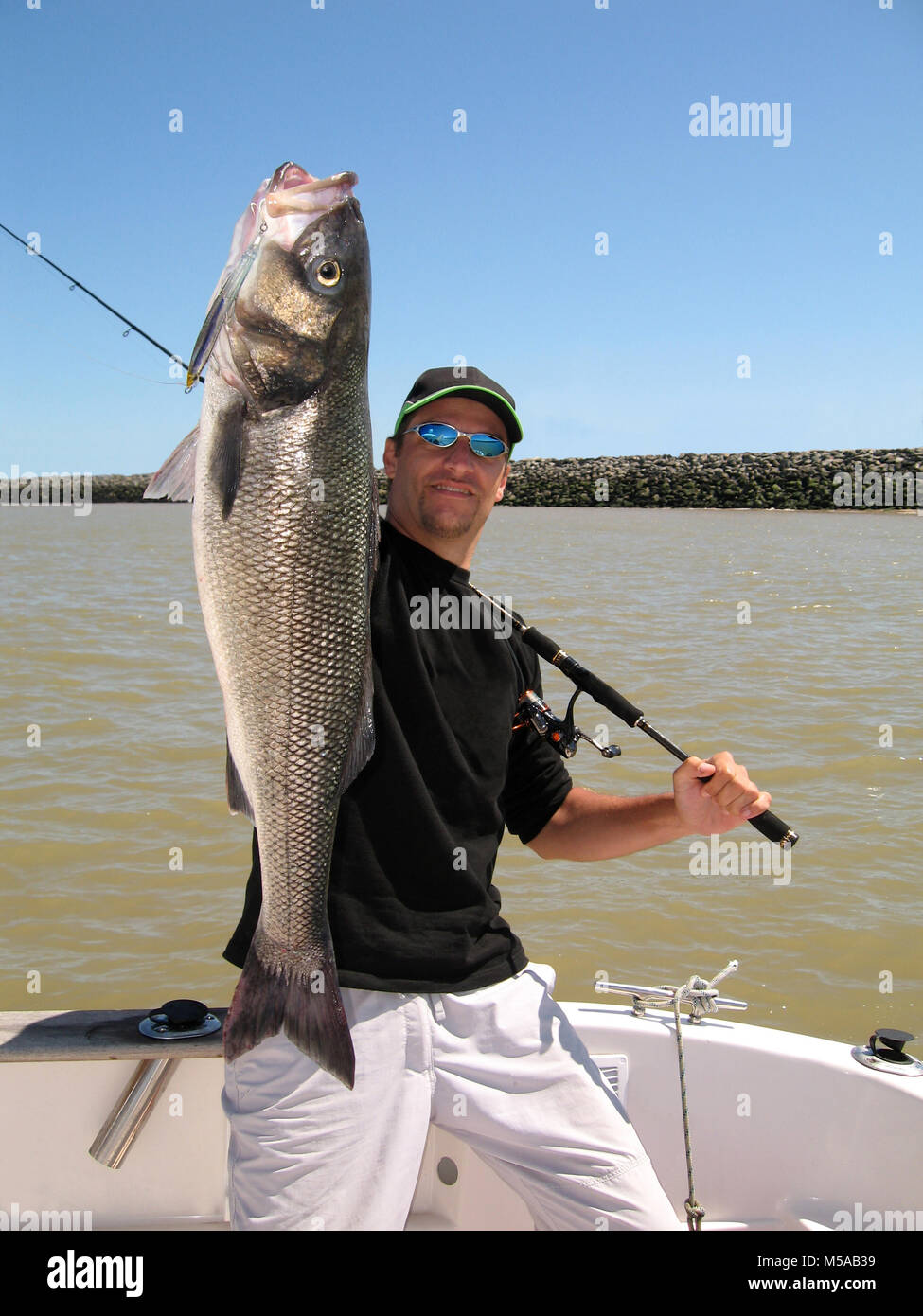 Lucky fisherman tenendo un grande mare bass Foto Stock