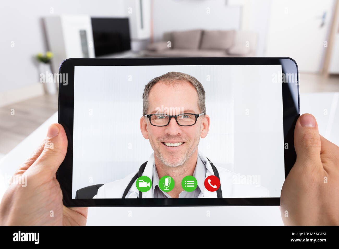 Close-up di una persona le videoconferenze con felice medico maschio sulla tavoletta digitale Foto Stock
