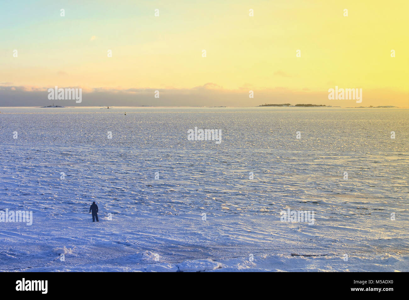 Silhouette di un uomo che espone a camminare sul mare ghiacciato a dusktime a Helsinki in Finlandia. Foto Stock