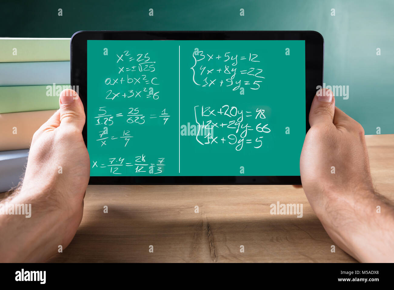 Close-up di mano di una persona Azienda digitale compressa con equazioni matematiche sullo schermo sulla scrivania Foto Stock