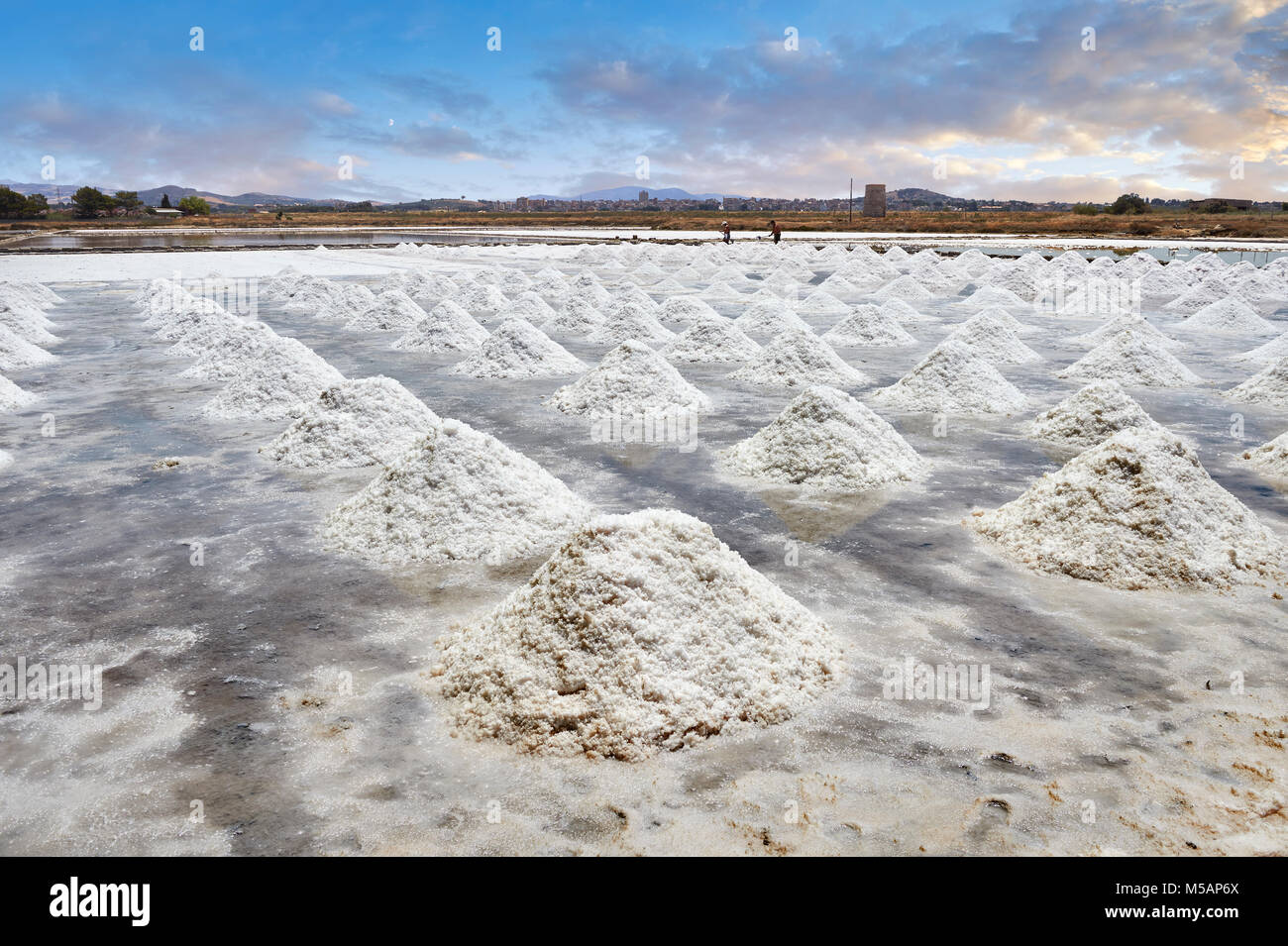 Foto e immagini di uomini la raccolta e lo scavo di sale in una padella di sale nella periferia di Trapani, Sicilia Foto Stock
