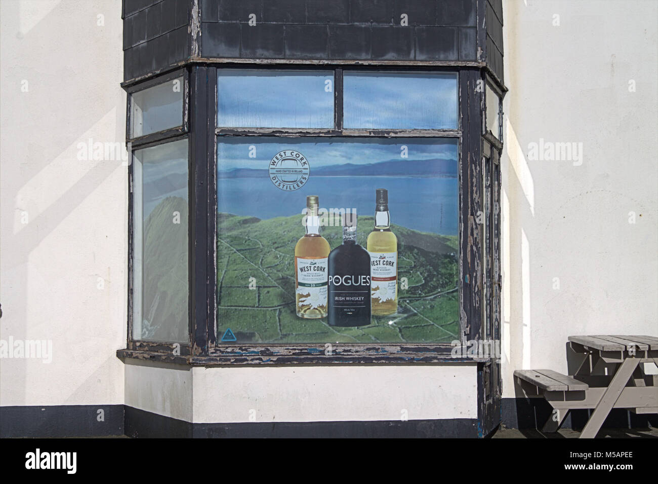 Tre whisky irlandese di bottiglie come parte di un annuncio pubblicitario in un pub finestra. Foto Stock