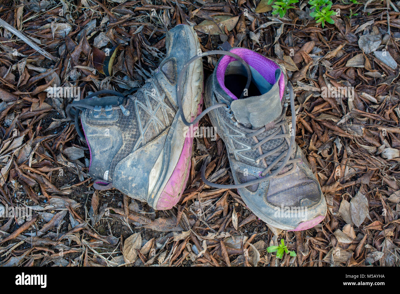 Coppia di vecchi, fangoso scarponcini da trekking sul terreno per illustrare il concetto di avventura all'aperto Foto Stock