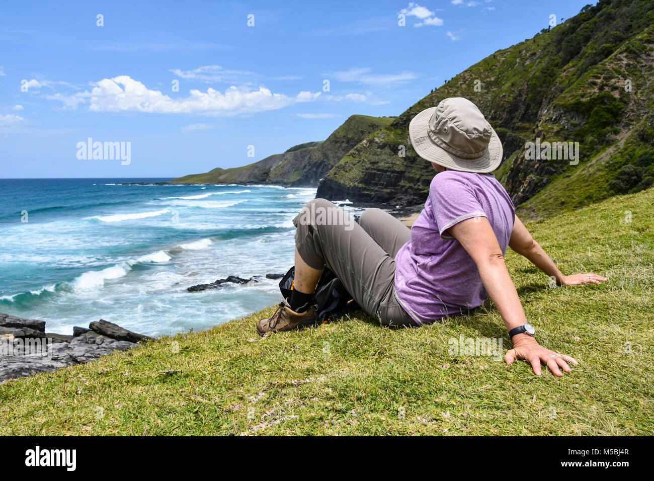 Una femmina di un escursionista in focus seduta godendo la vista del litorale sul sentiero che dalla baia di caffè all'Oceano Indiano nel Capo orientale al Wild Co Foto Stock