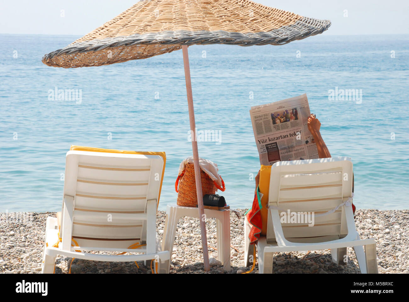 Donna lettura giornale turco sulla spiaggia Foto Stock