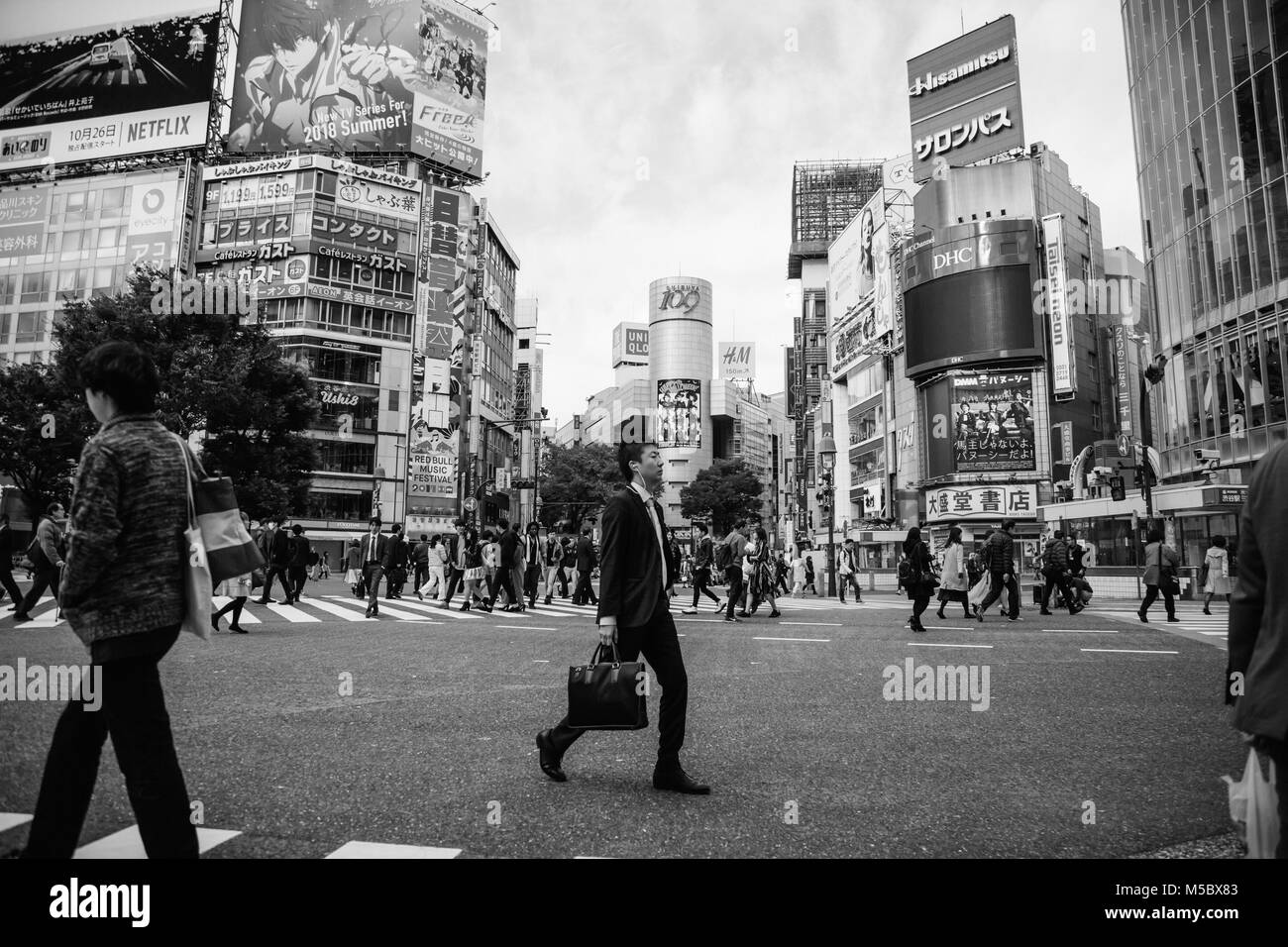 Un business uomo attraversa la strada in Shibuya, Tokyo Foto Stock