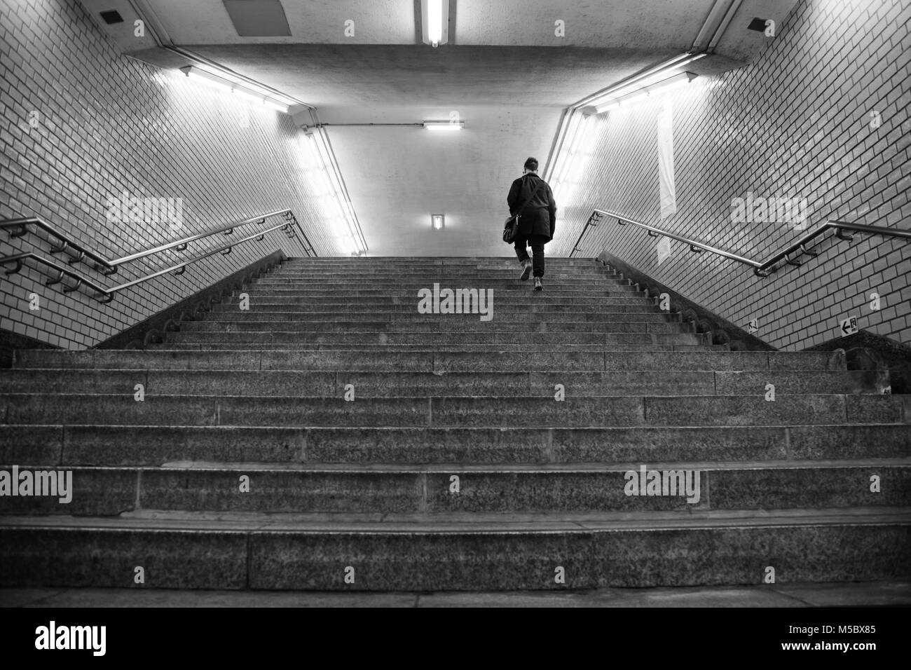 Un uomo cammina su per le scale in una stazione della metropolitana Foto Stock
