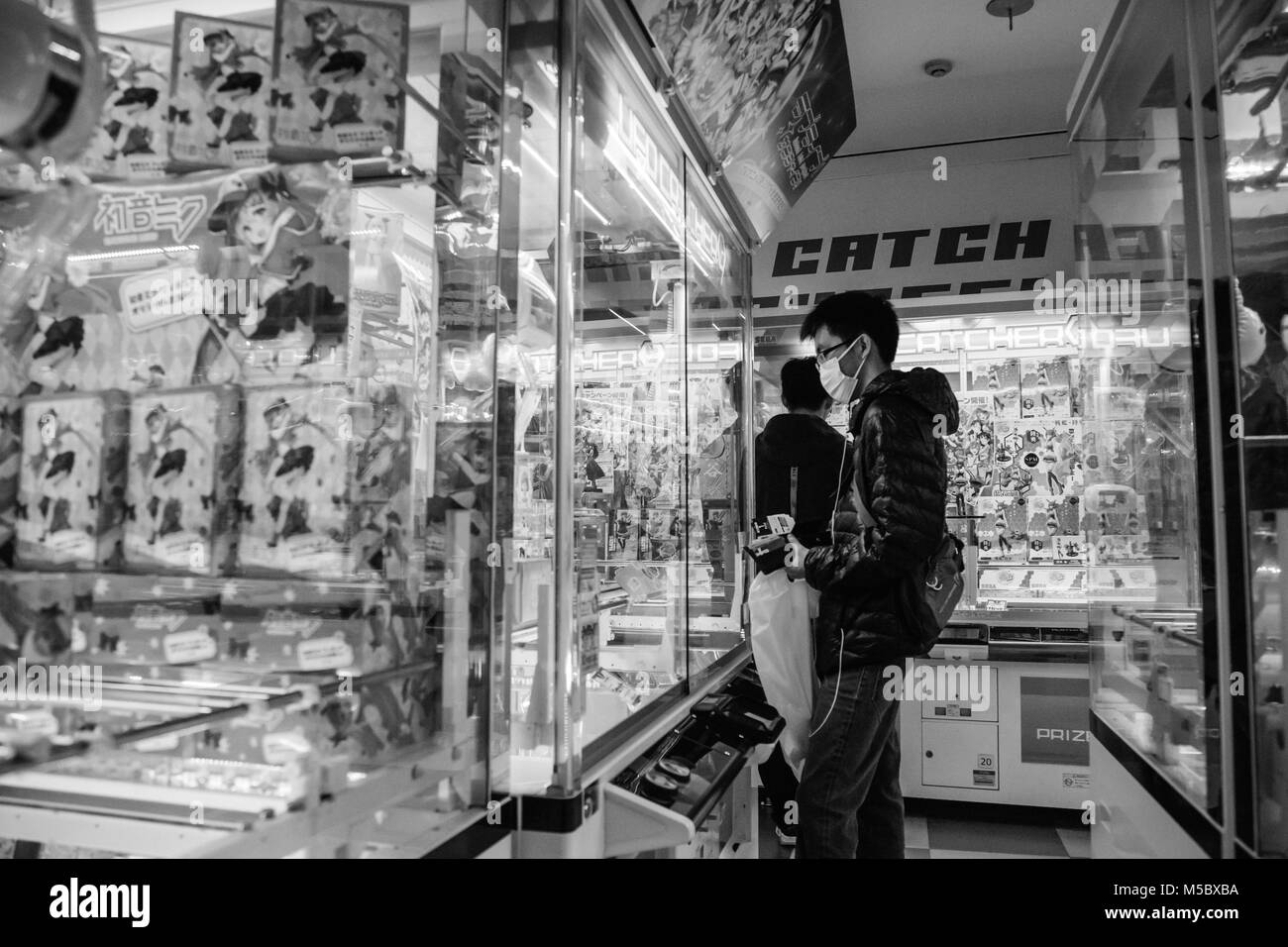 Giapponese 20-somethings giocare giochi arcade per i premi di Shinjuku, Tokyo. Foto Stock