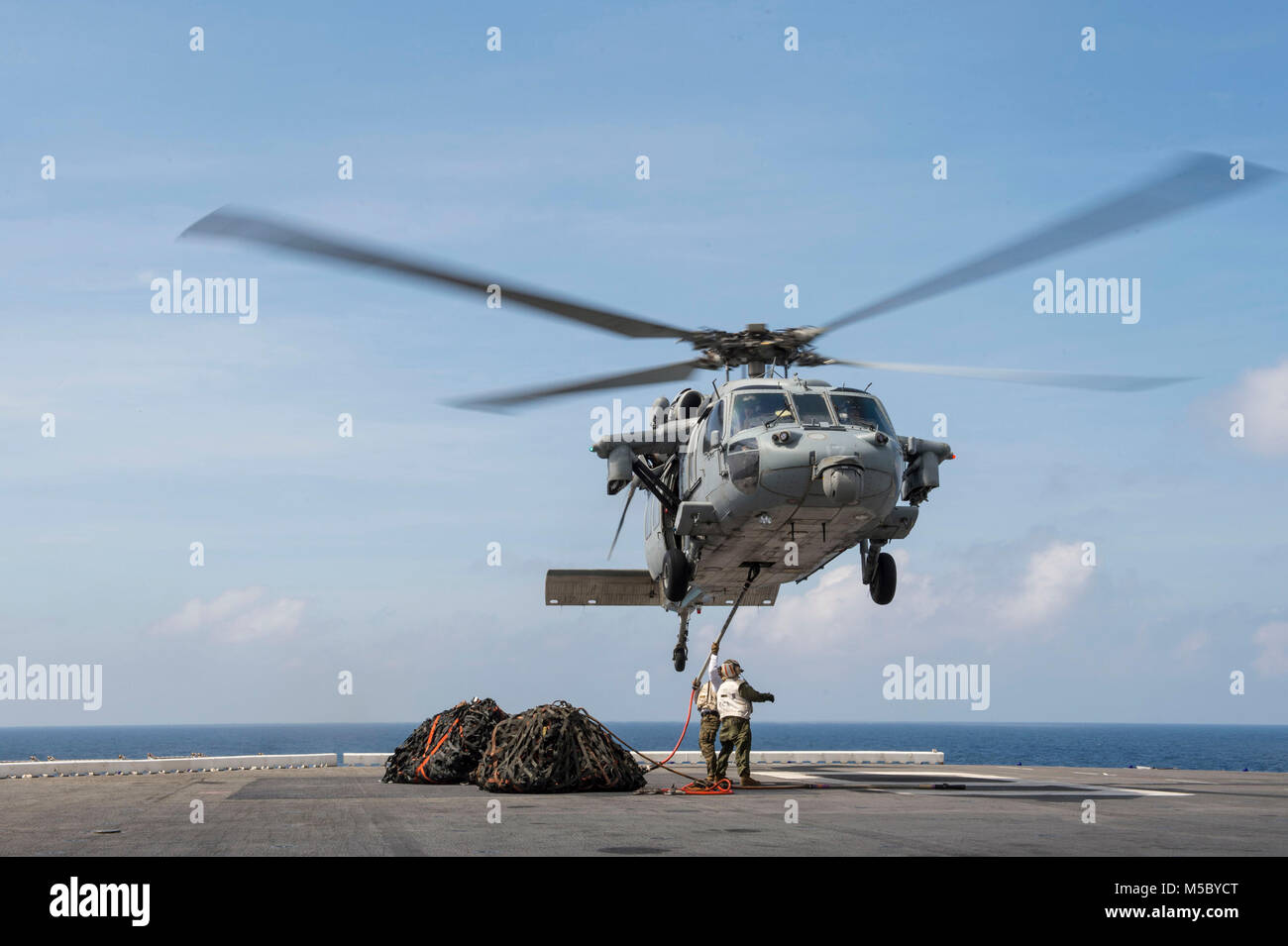 180221-N-NB544-197 sul Mare del Sud della Cina (feb. 21, 2018) Sgt. Kashaun Thompson, da Brooklyn, N.Y., assegnato al 3d Divisione Marine, ganci reti da carico per un MH-60S Sea Hawk, assegnato al 'Sea Cavalieri' di elicottero di mare squadrone di combattimento (HSC) 22, a bordo di un assalto anfibio nave USS Bonhomme Richard (LHD 6) durante un rifornimento in mare con il Henry J. Kaiser-class flotta oliatore di rifornimento USNS Walter S. Diehl (T-AO 193). Bonhomme Richard è operativo nell'Indo-Pacifico regione come parte di un regolarmente programmata di pattugliamento e fornisce una rapida capacità di risposta in caso di un livello regionale di contin Foto Stock