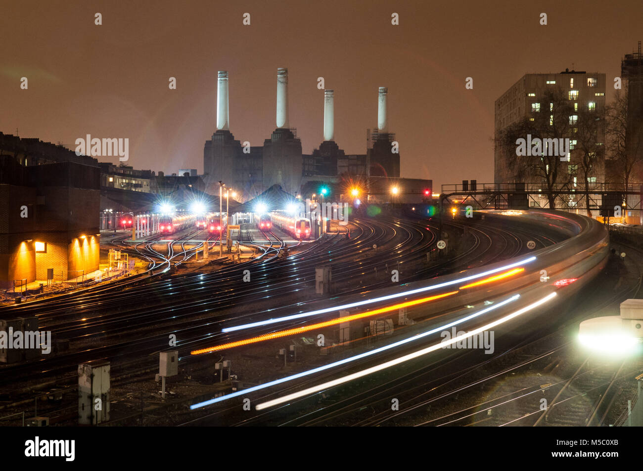 London, England, Regno Unito - 12 Gennaio 2013: Sud i treni passano Battersea Power Station su un approccio alla stazione Victoria di Londra di notte. Foto Stock