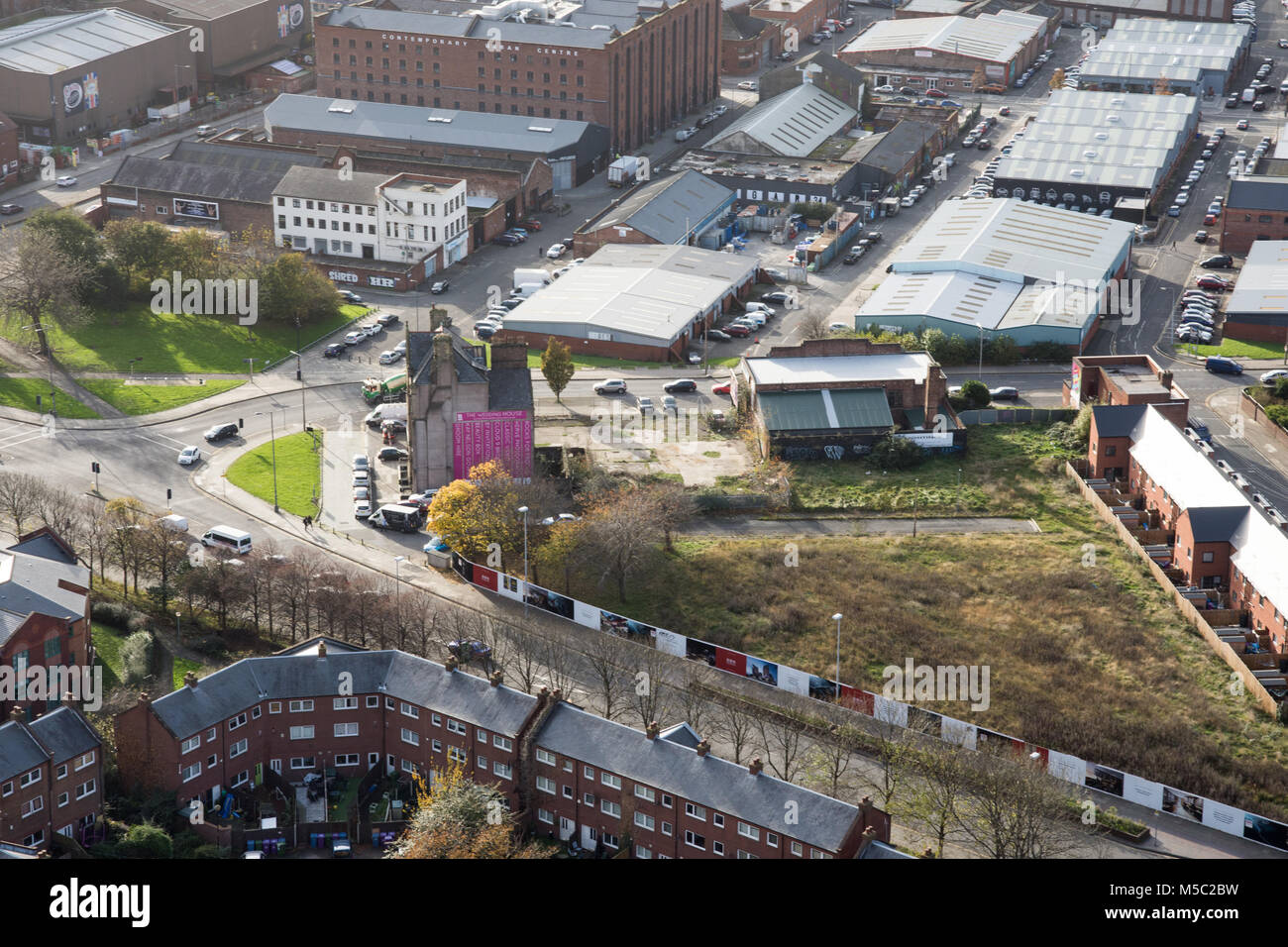 Liverpool, in Inghilterra, Regno Unito - 9 Novembre 2017: Case al fianco di un appezzamento di terra desolata in mezzo di rigenerazione, e magazzini e fabbriche o Foto Stock