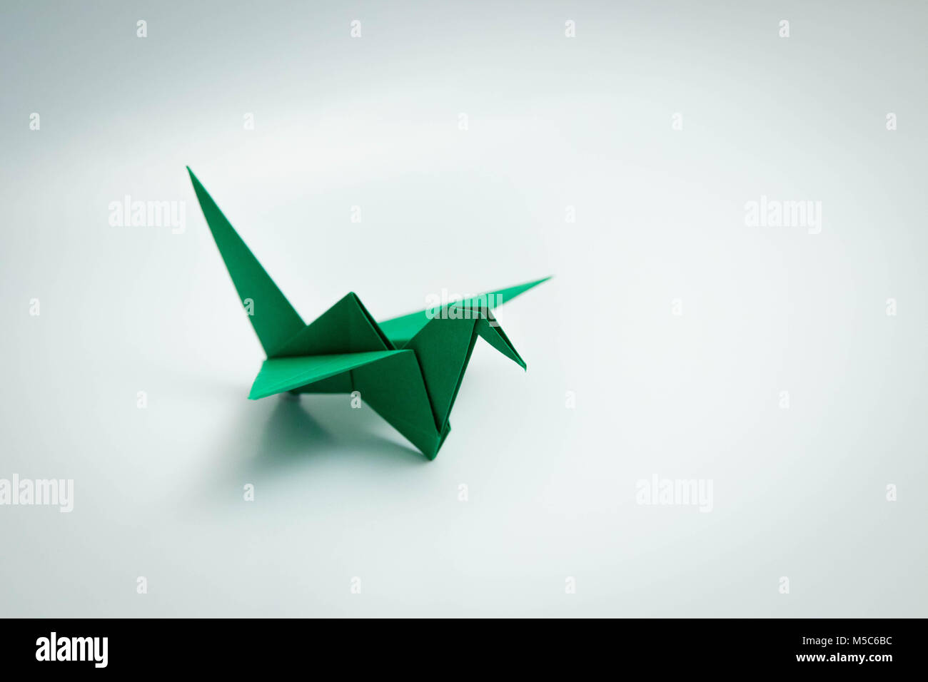 Unico uccello verde origami isolato su bianco Foto Stock